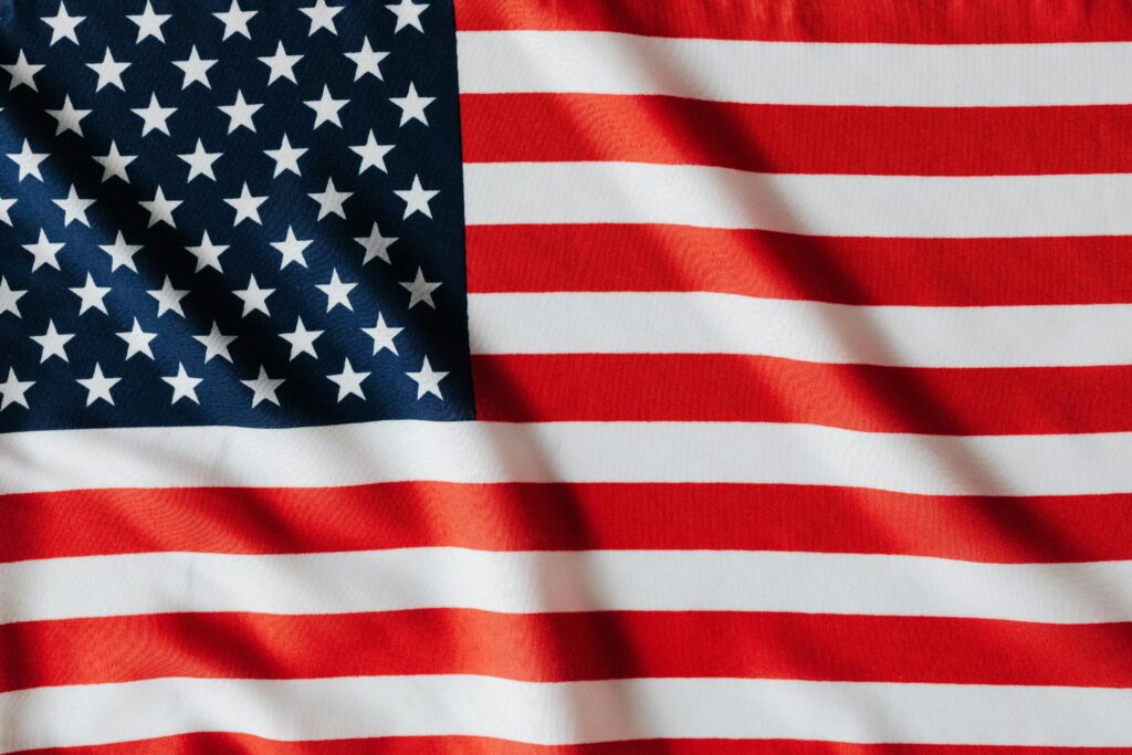 Flying national flag of United Stated of America with red and white stripes and white stars on blue square